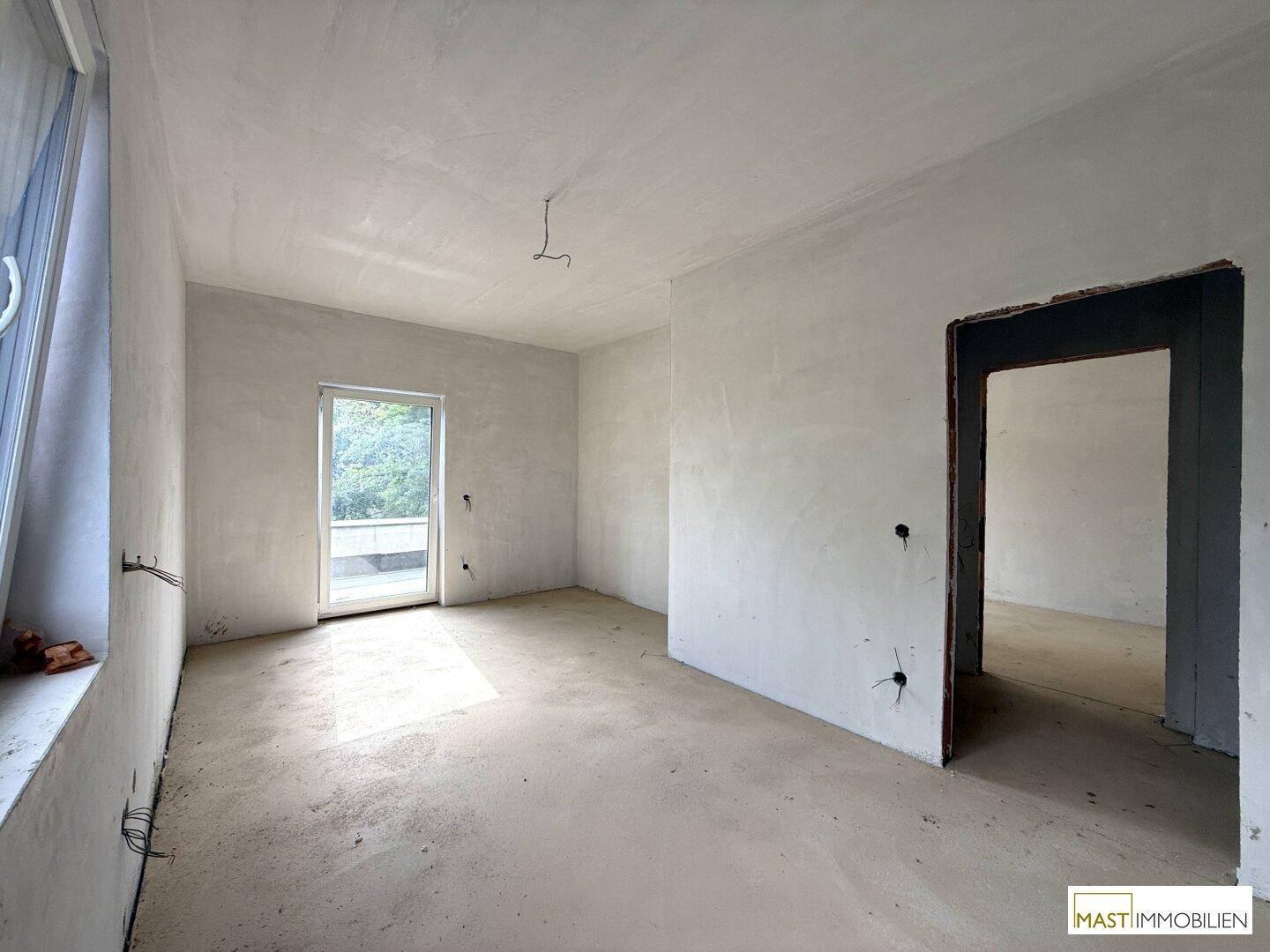 Heller Rohbau-Raum mit großem Fenster und Tür, ideal für ein Schlafzimmer oder Büro.