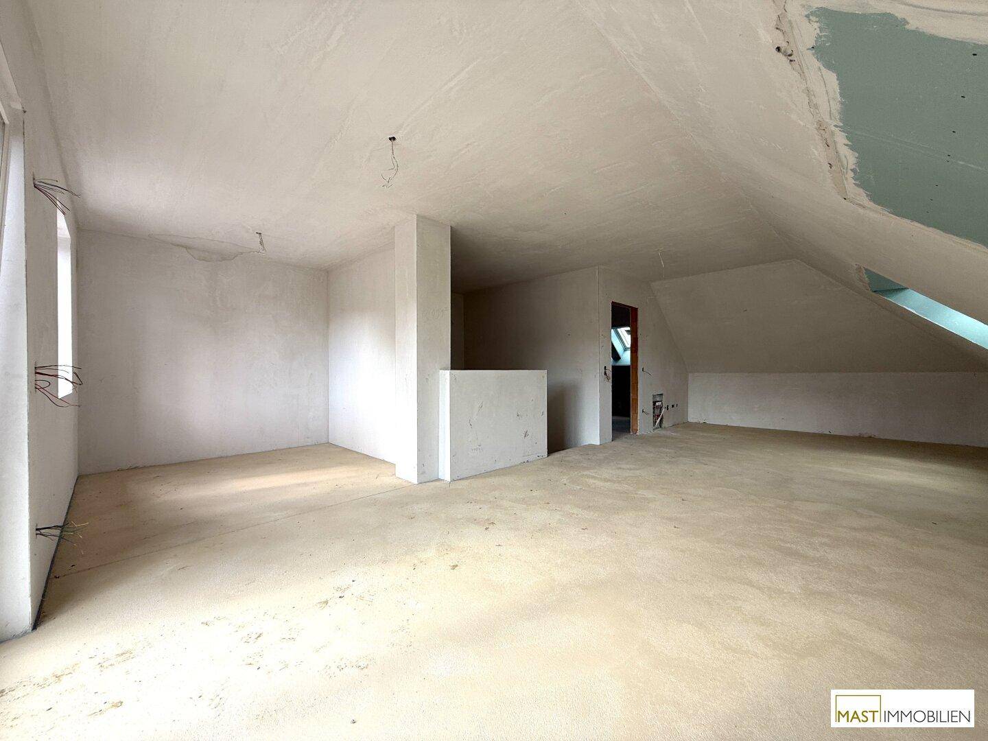 Geräumiger Dachboden im Rohbau mit schrägen Wänden und viel Potenzial.