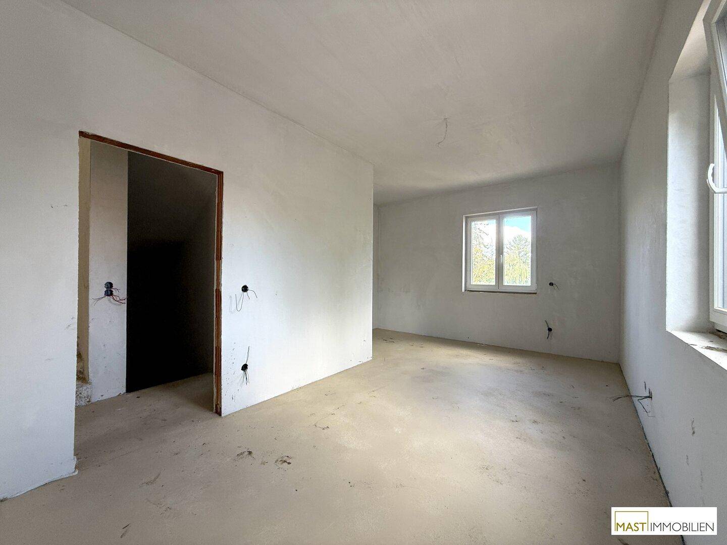 Rohbau-Zimmer mit zwei Fenstern, die viel Tageslicht in den Raum lassen.