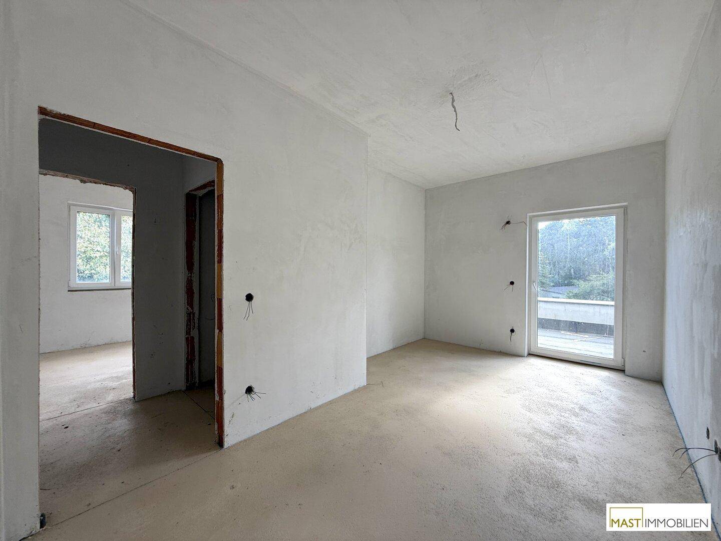 Helles Rohbau-Zimmer mit Fenster und Tür zu einem weiteren Raum oder Balkon.