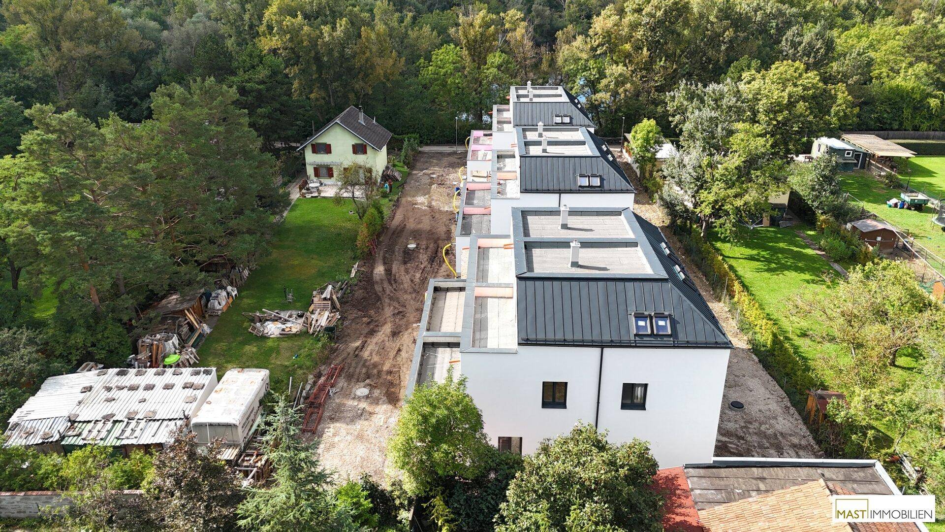 Drohnenansicht der Neubauten in einer grünen Umgebung mit angrenzenden älteren Häusern.