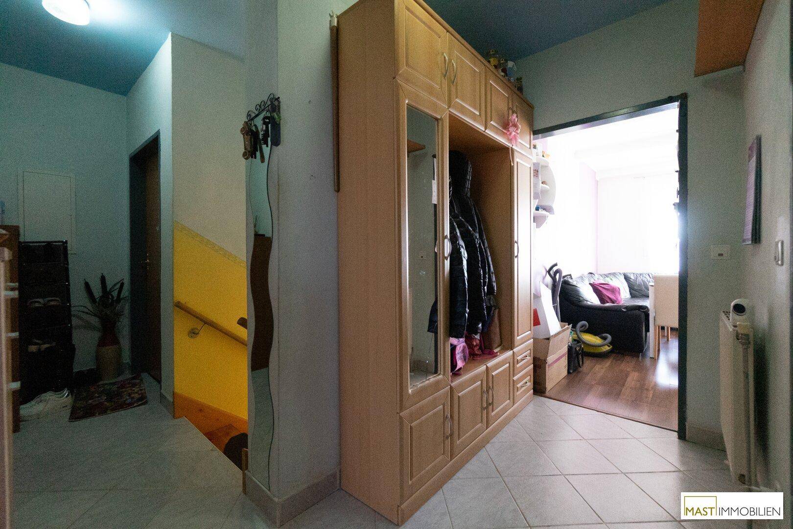 Flur mit großem Spiegelschrank, Fliesenboden und Blick in den Wohnbereich.