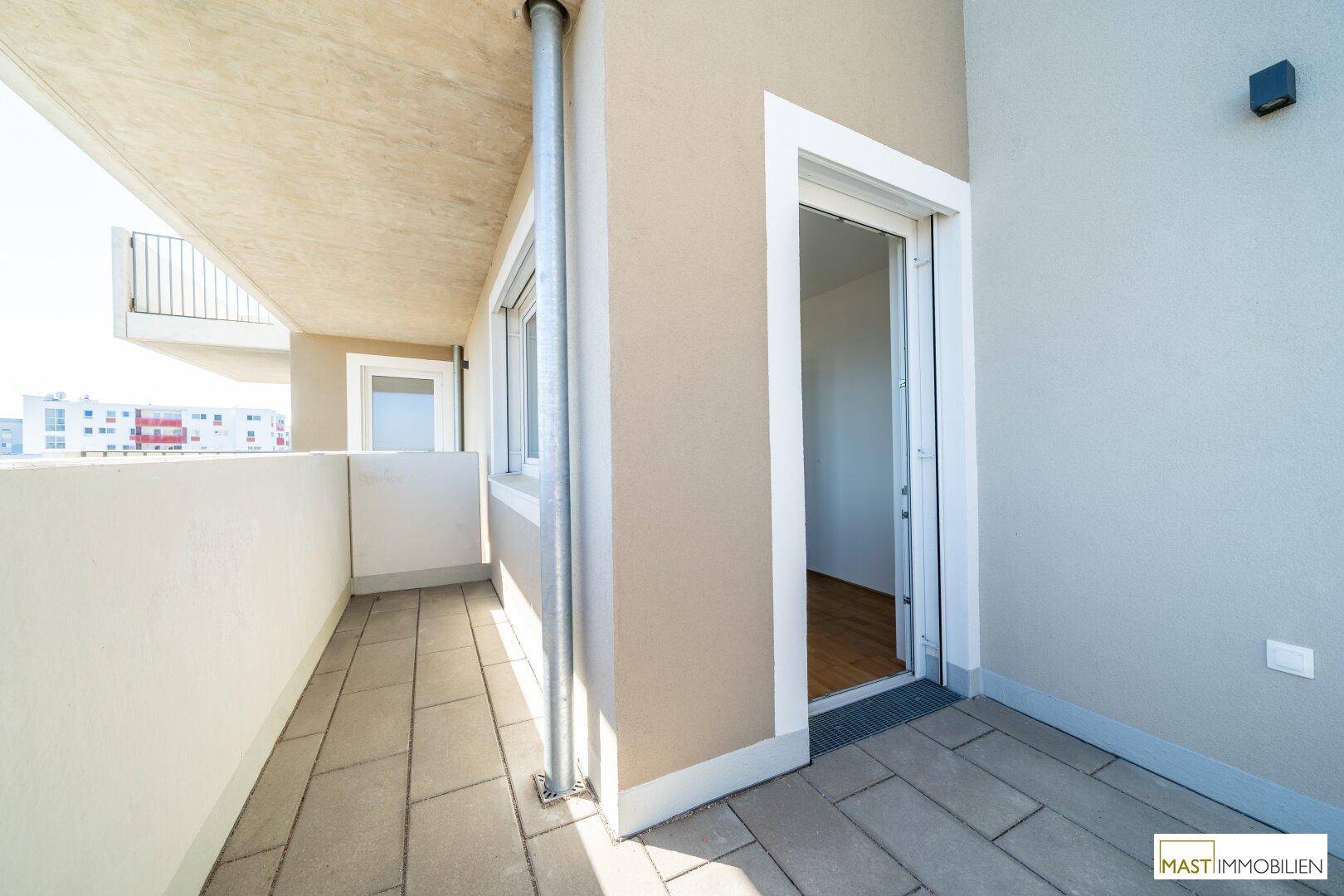 Heller Balkon mit Fliesenboden und Blick auf die Umgebung, zugänglich vom Innenbereich.