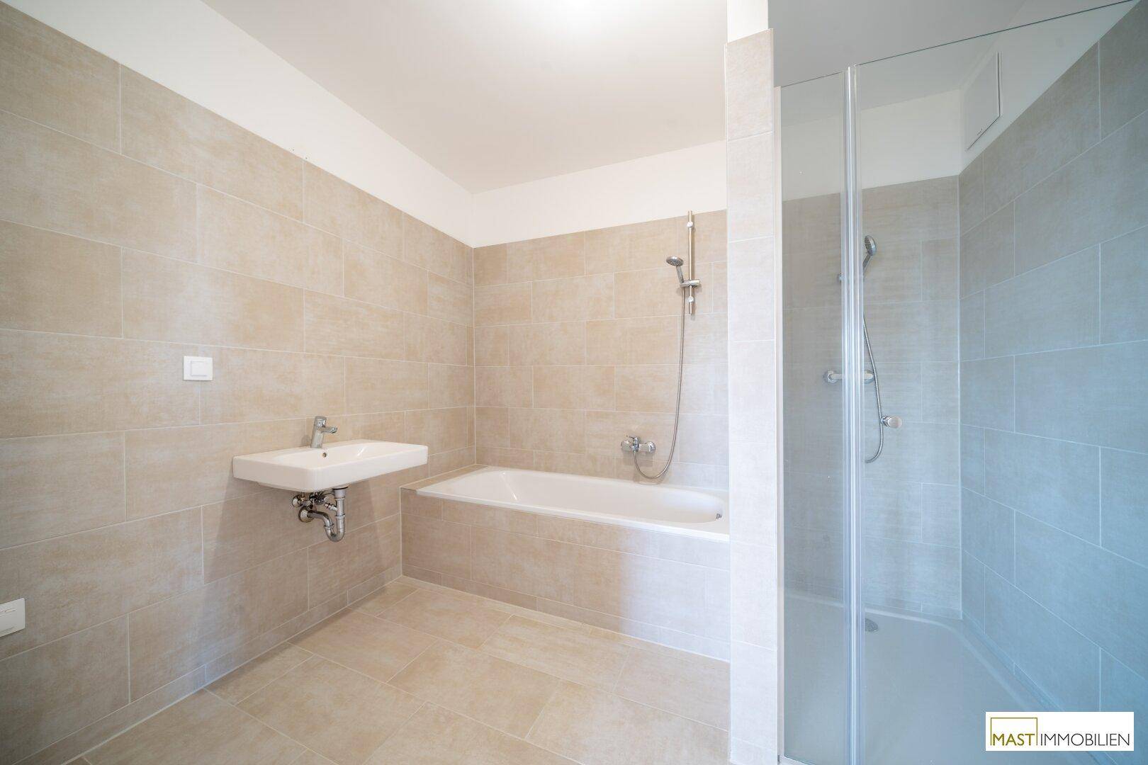 Modernes Badezimmer mit beigefarbenen Fliesen, Badewanne, Einzelwaschbecken und begehbarer Dusche.