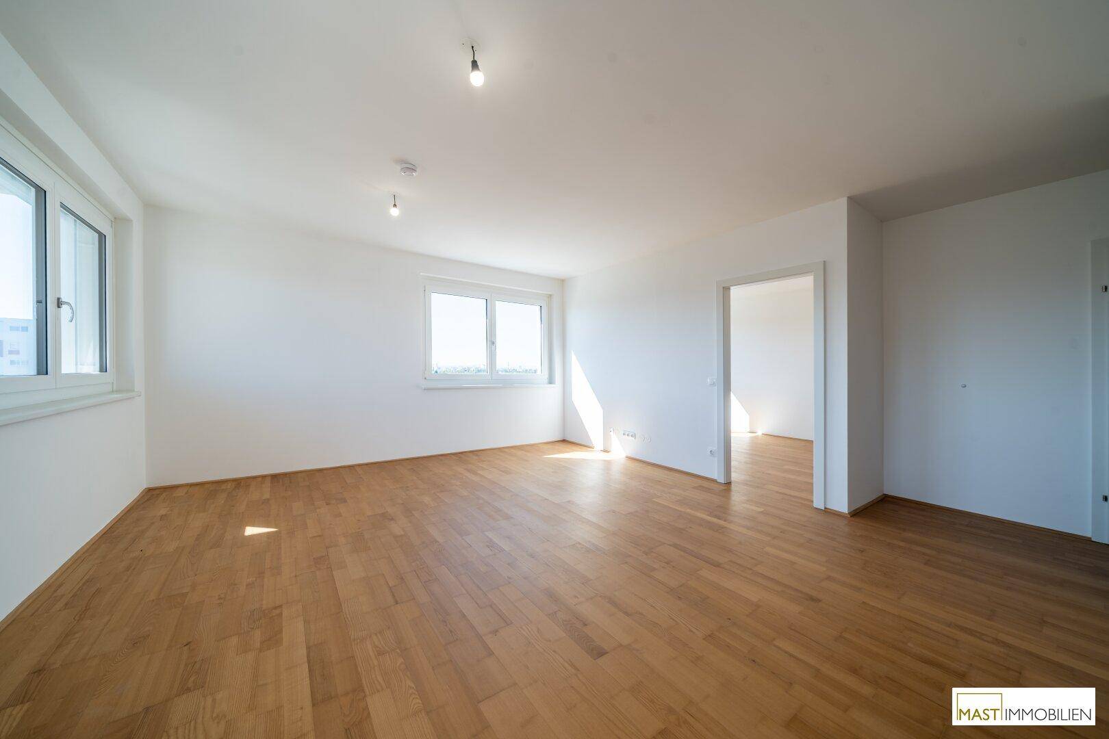 Geräumiger, heller Wohnbereich mit Parkettboden und einem Fenster, das viel Tageslicht hereinlässt.
