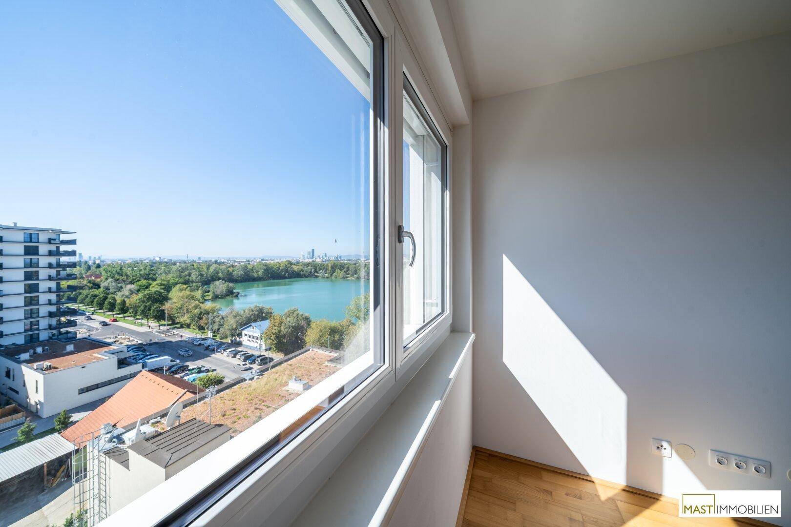 Heller Raum mit großem Fenster und beeindruckendem Blick auf den See und die Stadtlandschaft.