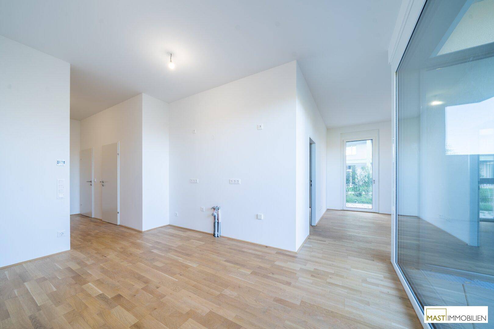 Heller Flur mit Parkettboden und Zugang zu weiteren Räumen sowie großen Fenstern, die Tageslicht hereinlassen.