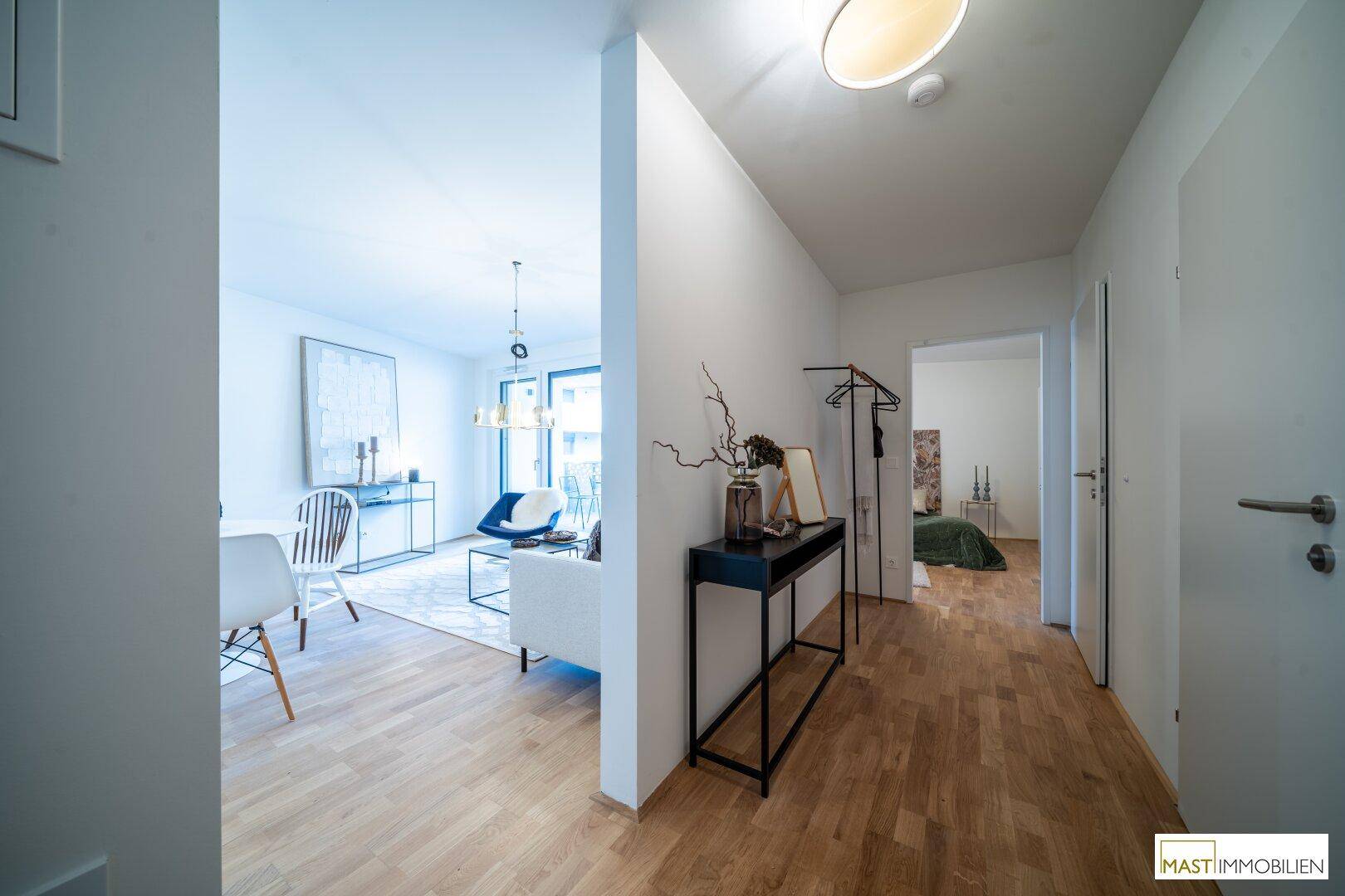 Moderner Flur mit Holzboden, Garderobe und Blick in den offenen Wohnbereich.