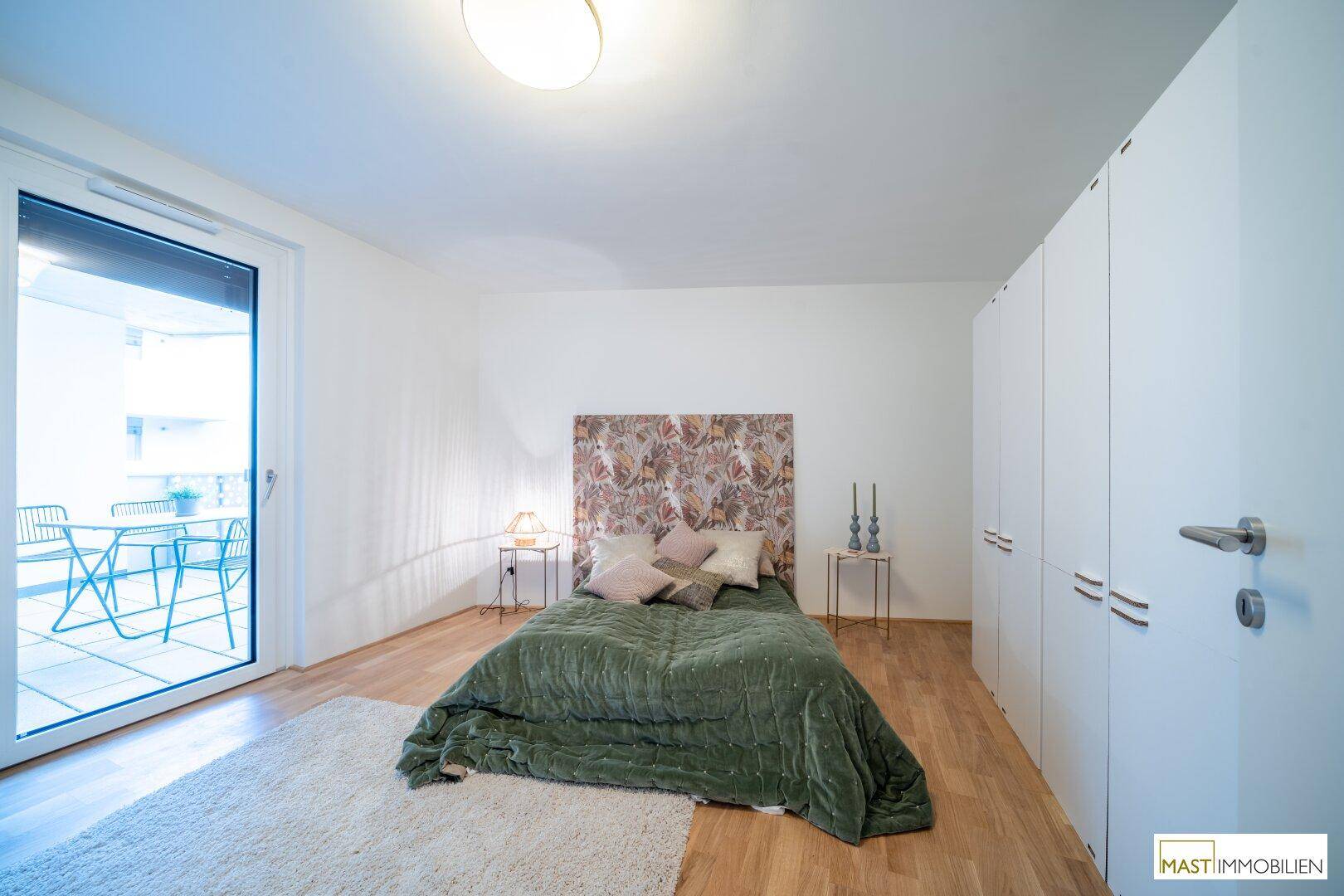 Helles Schlafzimmer mit großem Bett, Einbauschränken und direktem Balkonzugang.