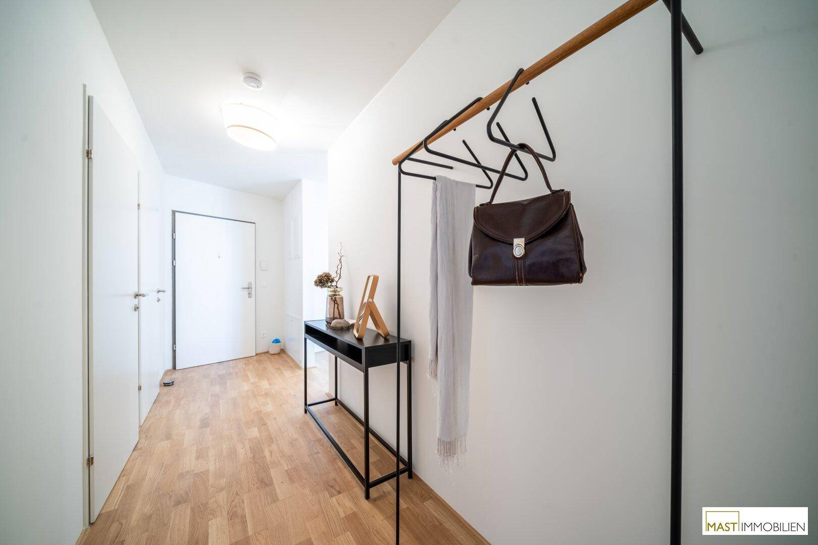 Eingangsbereich mit Holzboden und moderner Garderobe, führt zu weiteren Räumen.