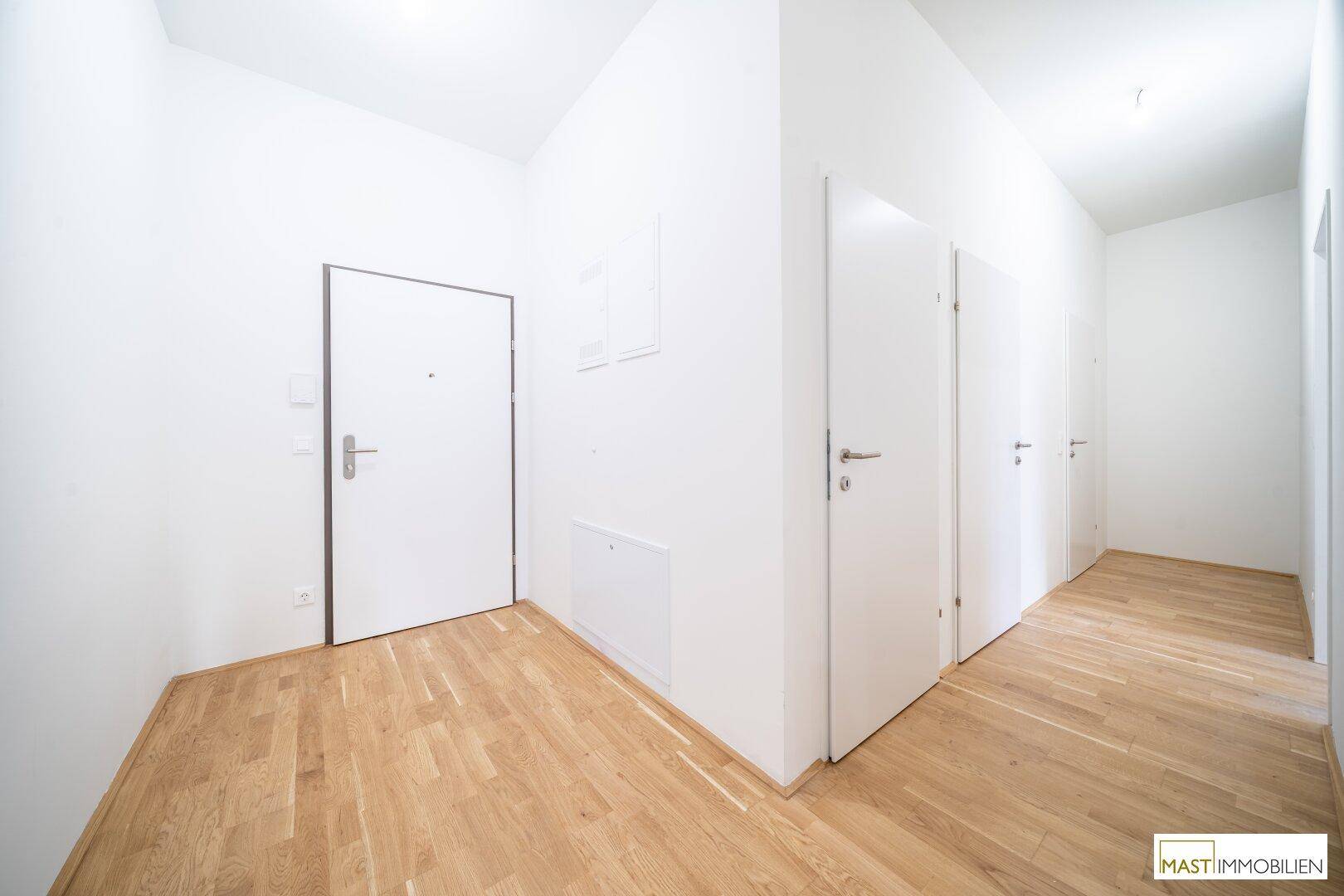 Heller Flur mit Holzboden und mehreren weißen Türen, der verschiedene Räume verbindet.