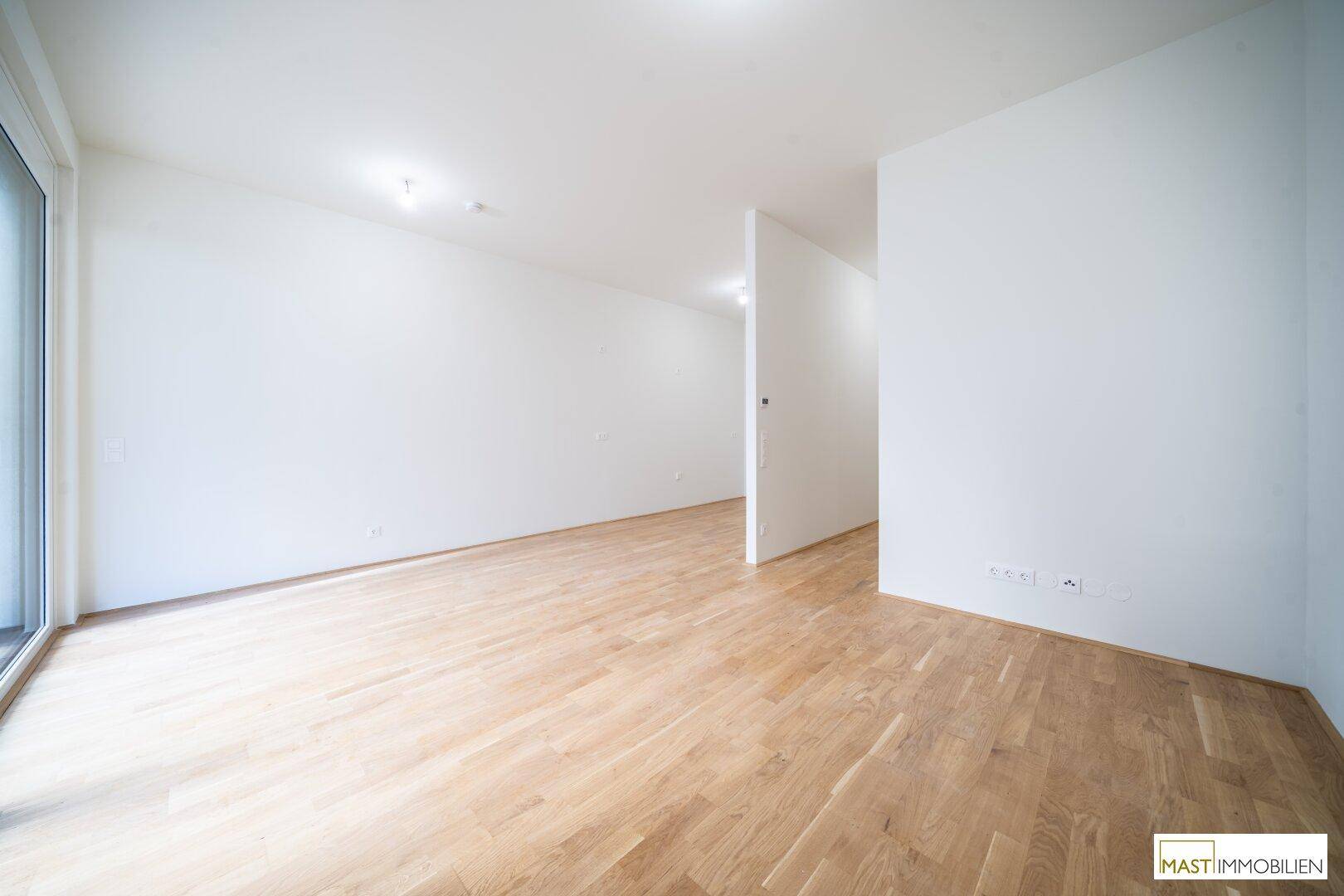Heller, leerer Raum mit hellem Holzparkett und großen Fenstern, bereit zur individuellen Gestaltung.