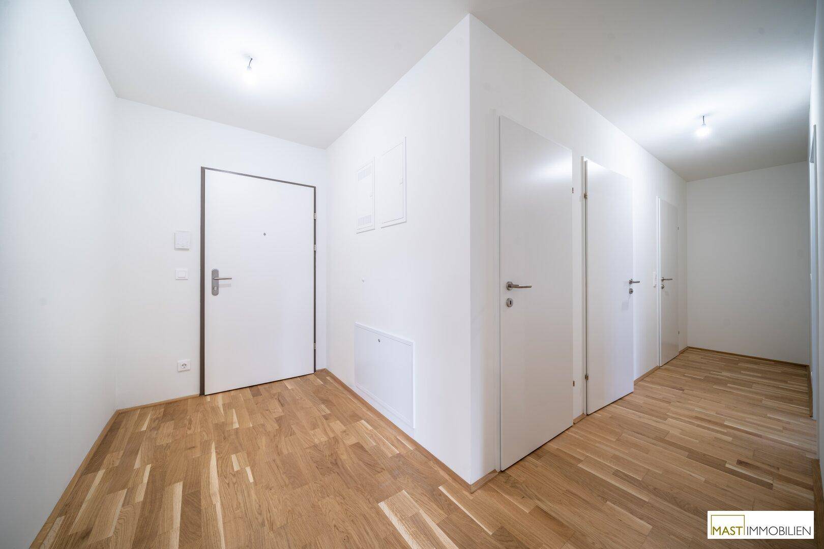 Moderner Eingangsbereich mit hellem Parkettboden und mehreren weißen Türen.
