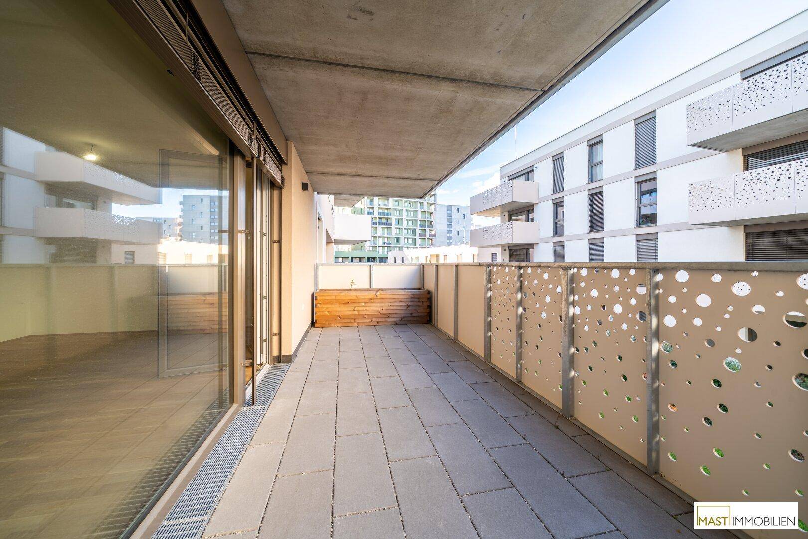 Geräumiger Balkon mit modernen Bodenfliesen und dekorativem Metallgeländer mit Blick auf die Umgebung.