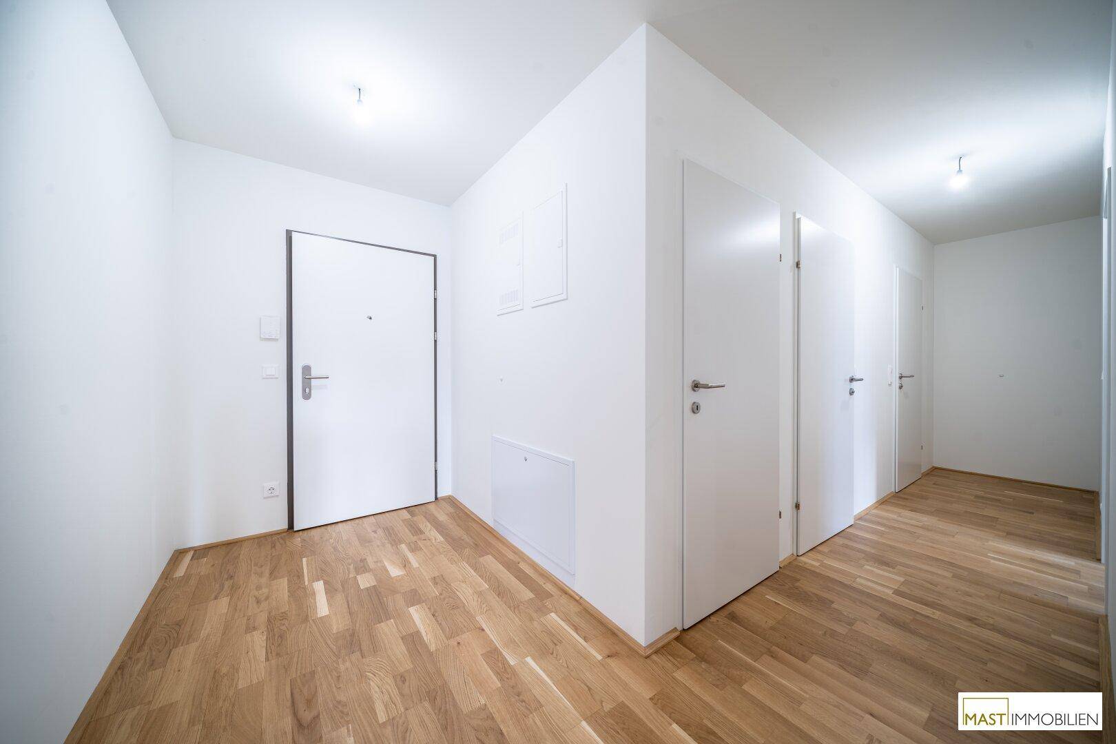 Heller Eingangsbereich mit Holzboden und mehreren Türen zu den angrenzenden Räumen.