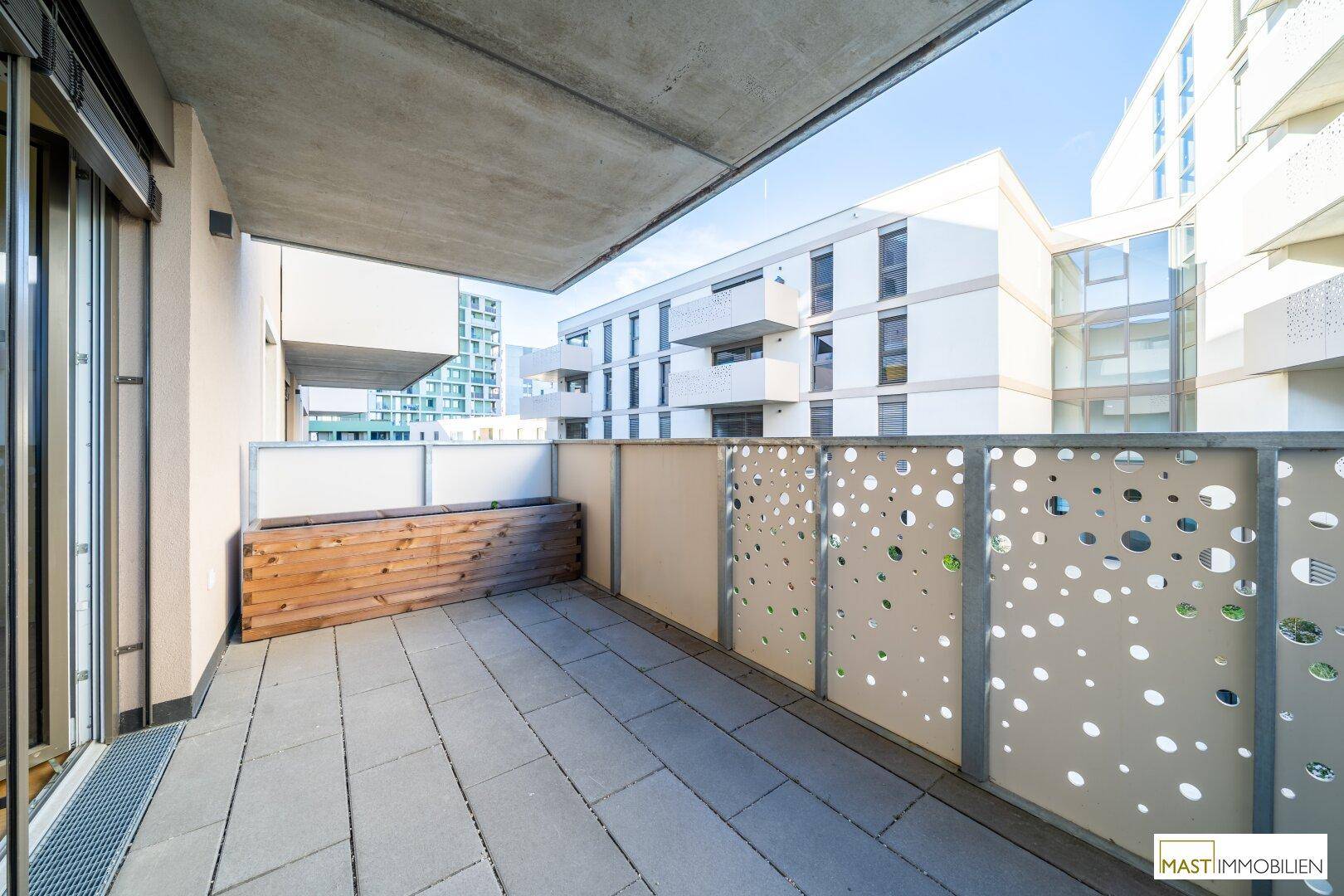 Moderner Balkon mit Blick auf umliegende Gebäude und dekorativen Lochblech-Elementen.