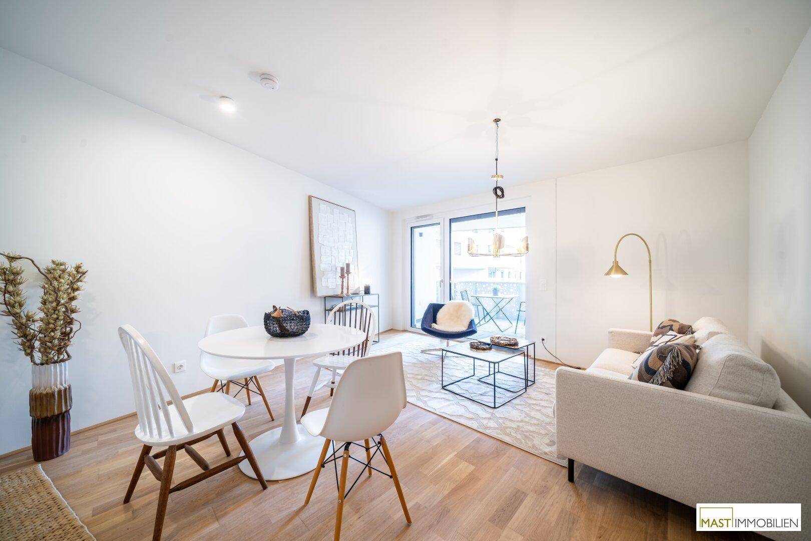 Heller Wohn-Essbereich mit beigem Sofa, modernem Esstisch und Zugang zu einem Außenbereich.