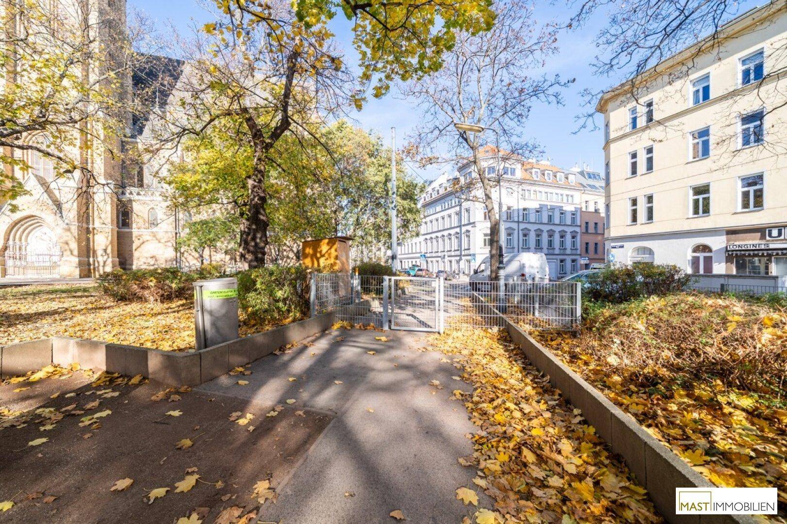 Herbstliche Straßenszene mit Bäumen, Gebäuden und einer Kirche im Hintergrund.