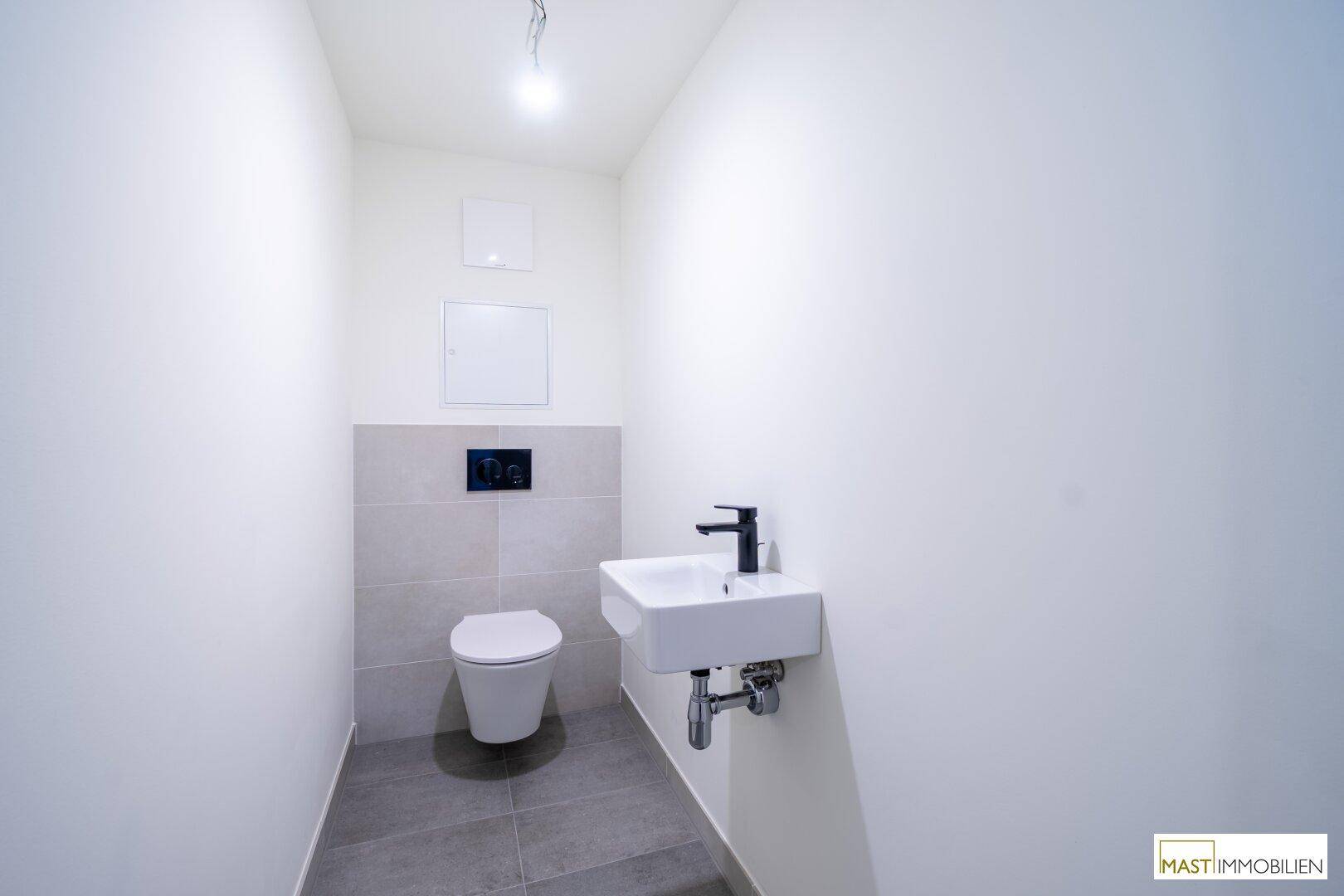 Kompaktes Gäste-WC mit wandhängender Toilette und kleinem Waschbecken.