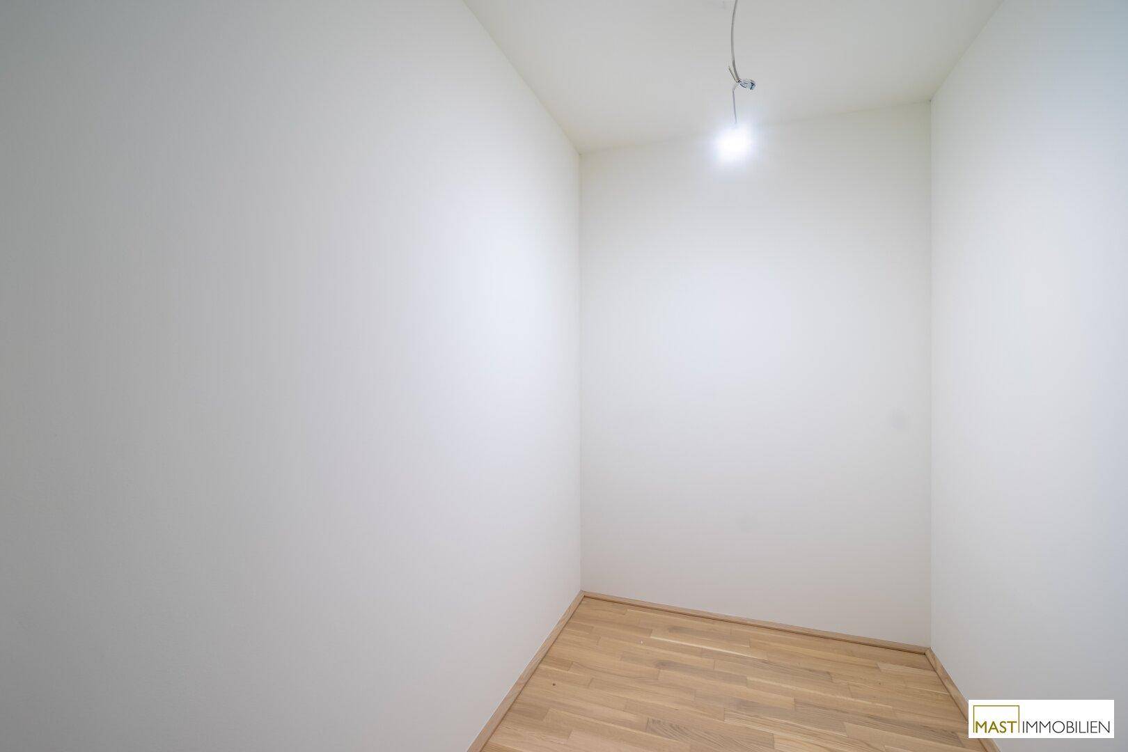 Kleiner, leerer Raum mit Parkettboden, der als Abstellraum oder begehbarer Kleiderschrank dienen könnte.