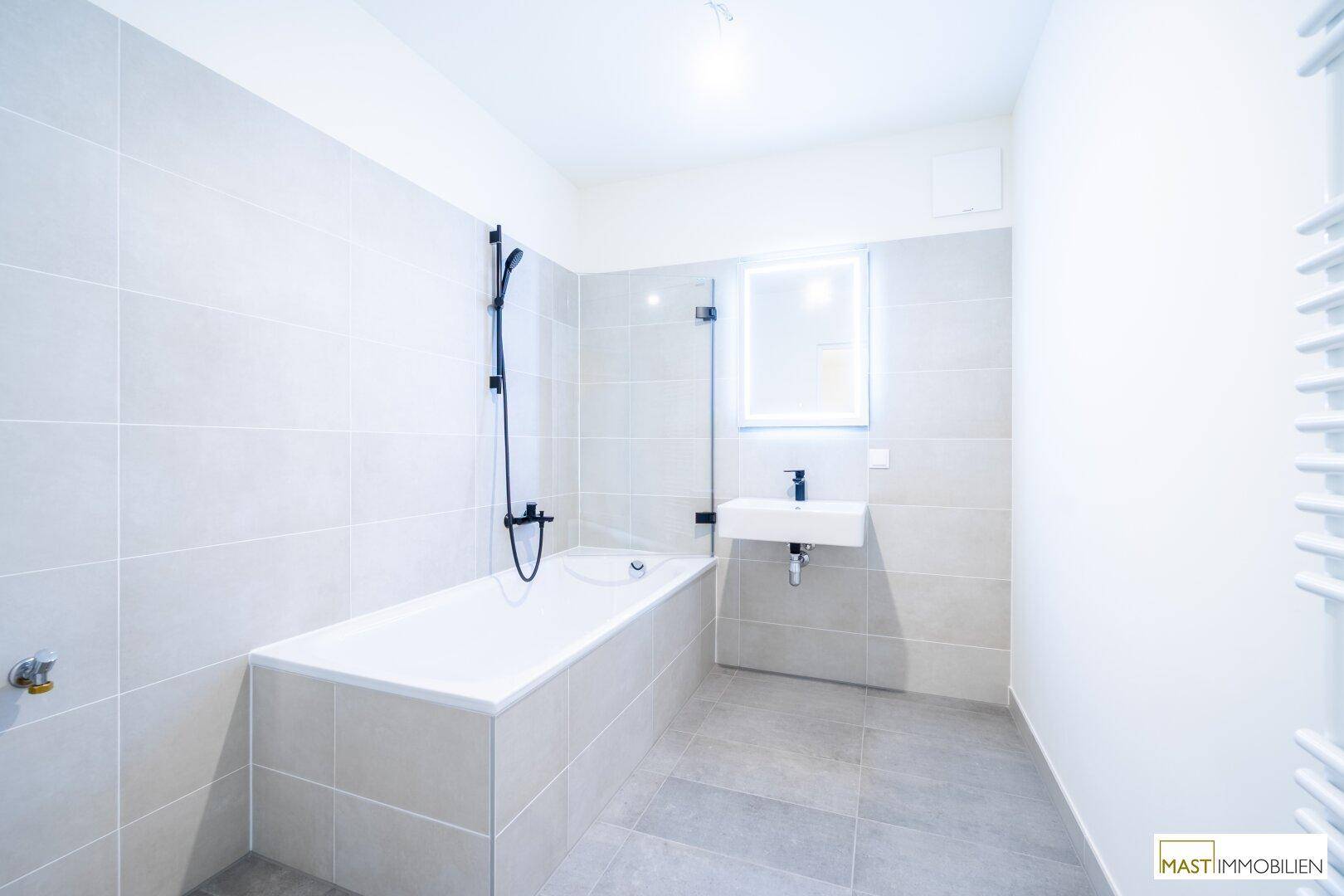 Modernes Badezimmer mit Badewanne, Duscharmatur, Waschbecken und beheiztem Handtuchhalter.