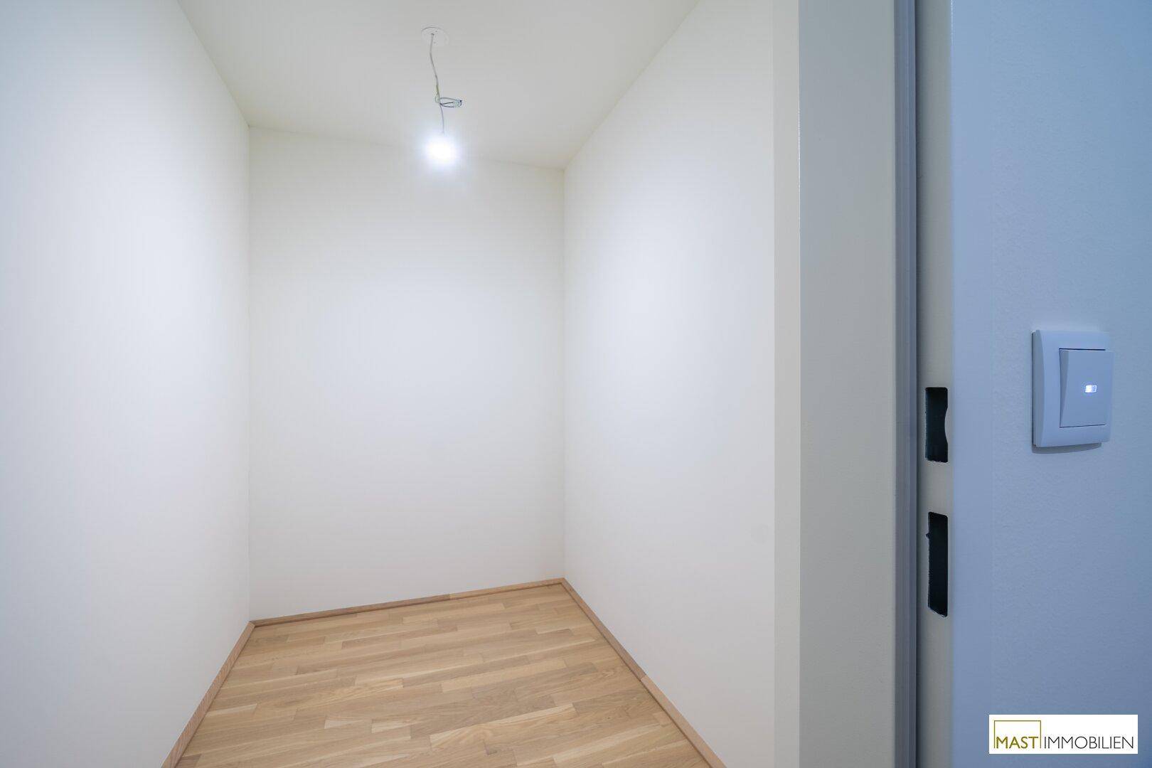 Kleiner, leerer Abstellraum mit Holzboden, ideal für zusätzlichen Stauraum oder als begehbarer Kleiderschrank.