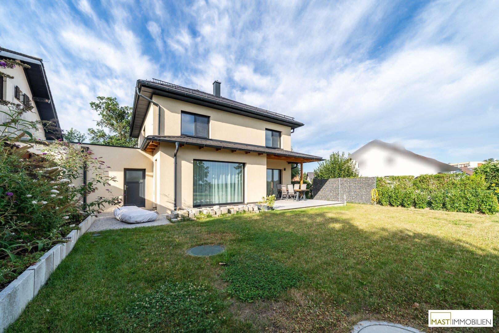 Rückansicht des Hauses mit großer Rasenfläche und umliegender Natur.