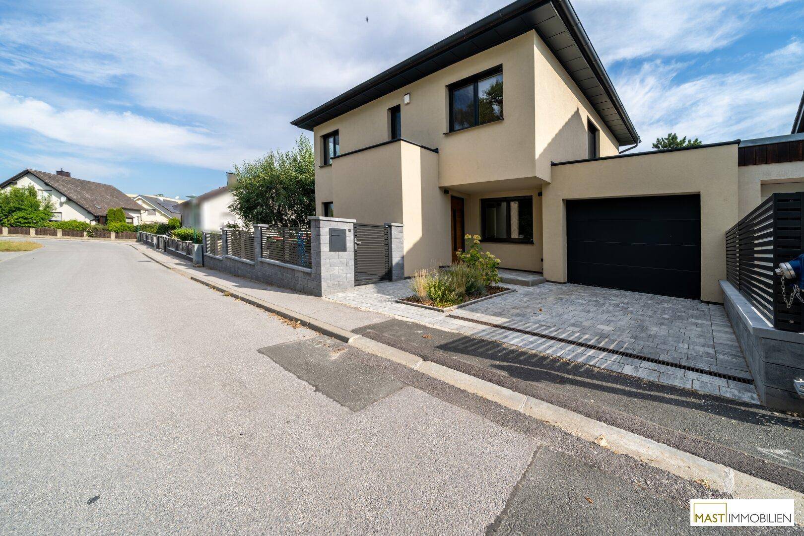 Gesamtansicht des modernen Hauses von der Straße mit Garage und Einfahrt.