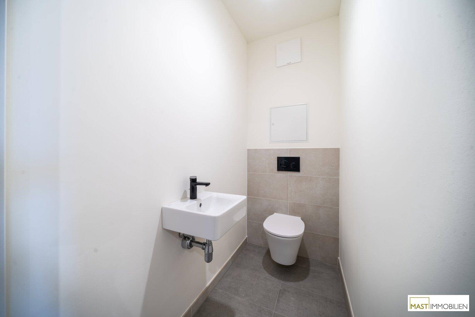 Modernes Gäste-WC mit wandhängender Toilette und kleinem Waschbecken.