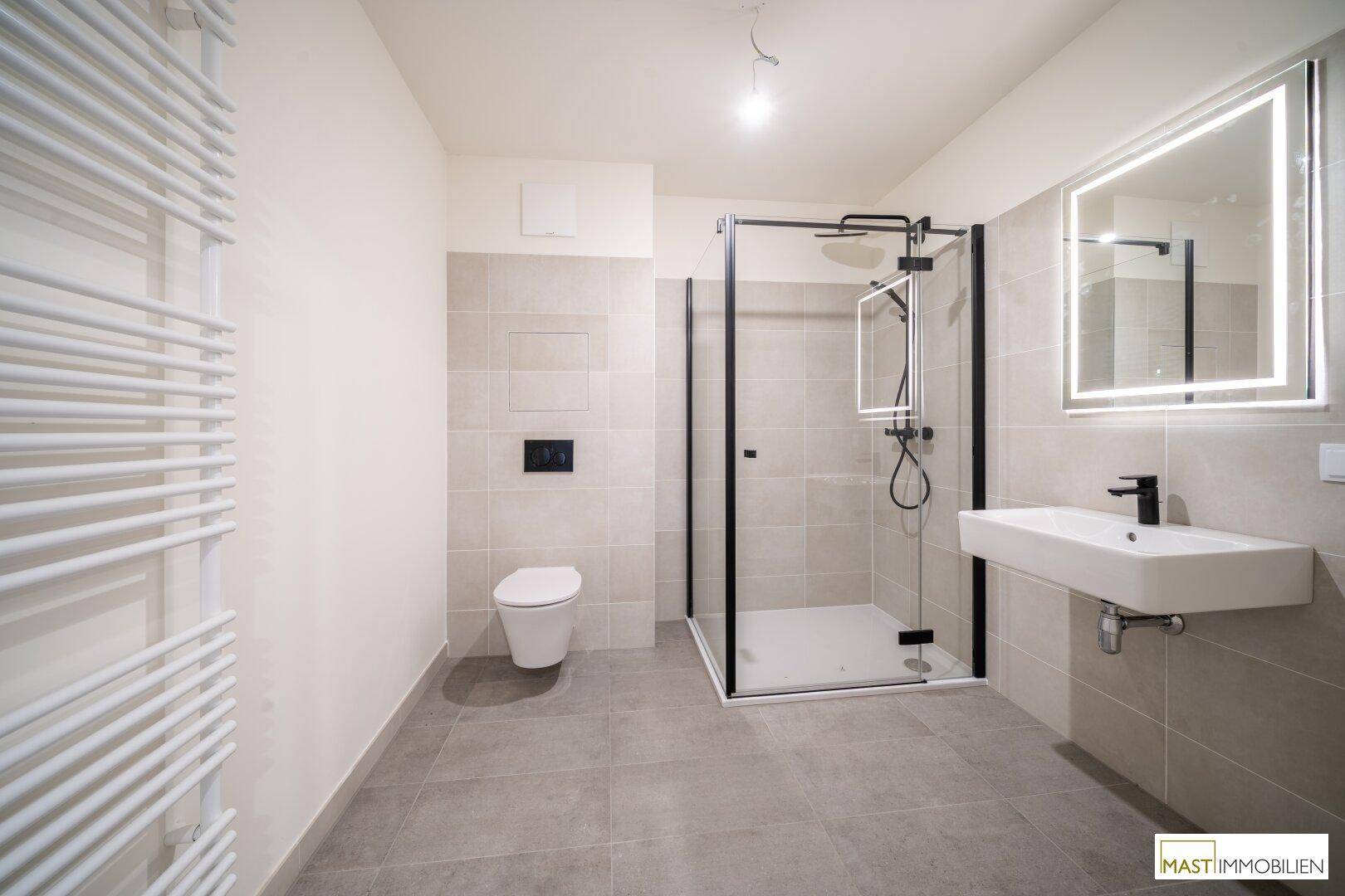 Modernes Badezimmer mit grauen Fliesen, ebenerdiger Dusche und beheiztem Handtuchhalter.