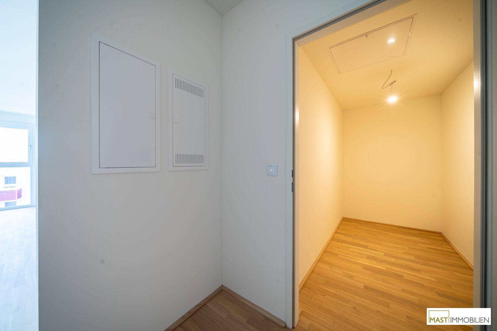 Kleiner Abstellraum mit Parkettboden und Zugangsklappen an der Wand, ideal für Haushaltsgeräte.