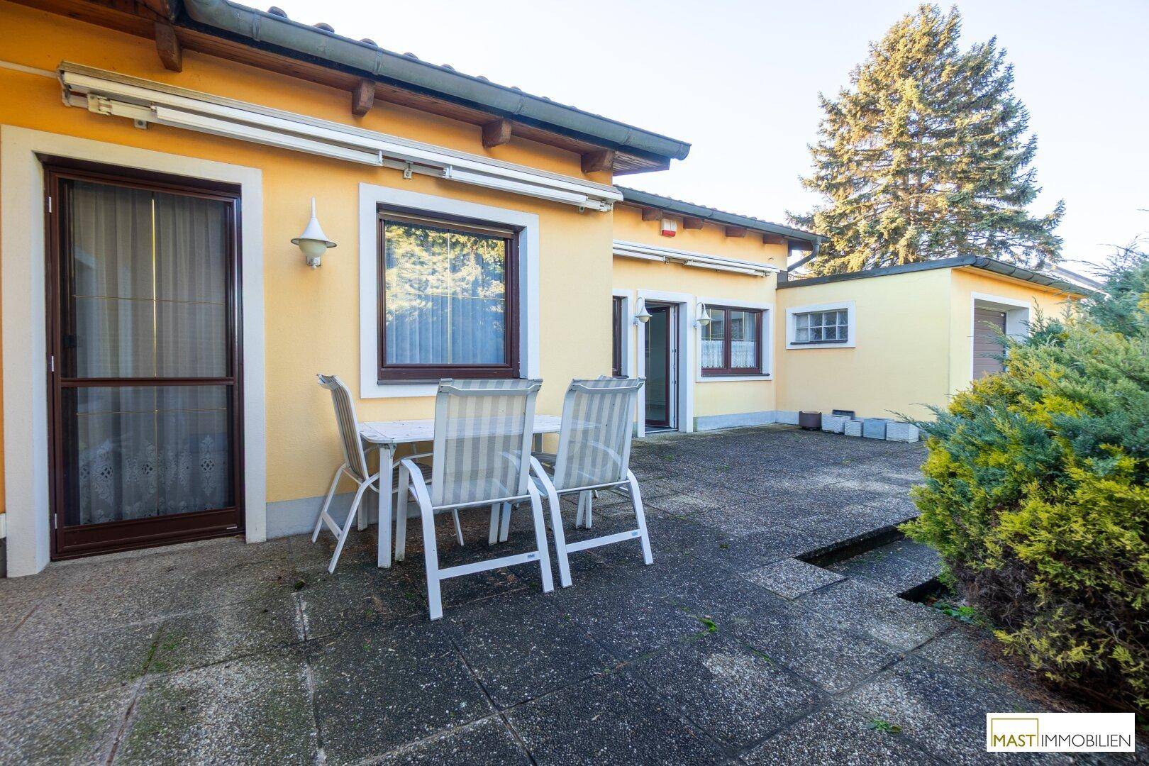 Gepflasterte Terrasse mit Gartenmöbeln und Markise.