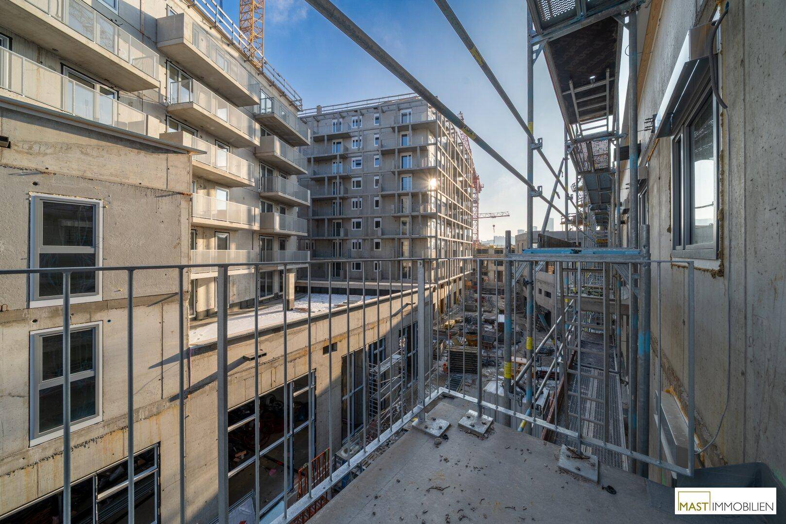 Blick von einem im Bau befindlichen Balkon auf weitere Neubauten und die Baustellenumgebung.
