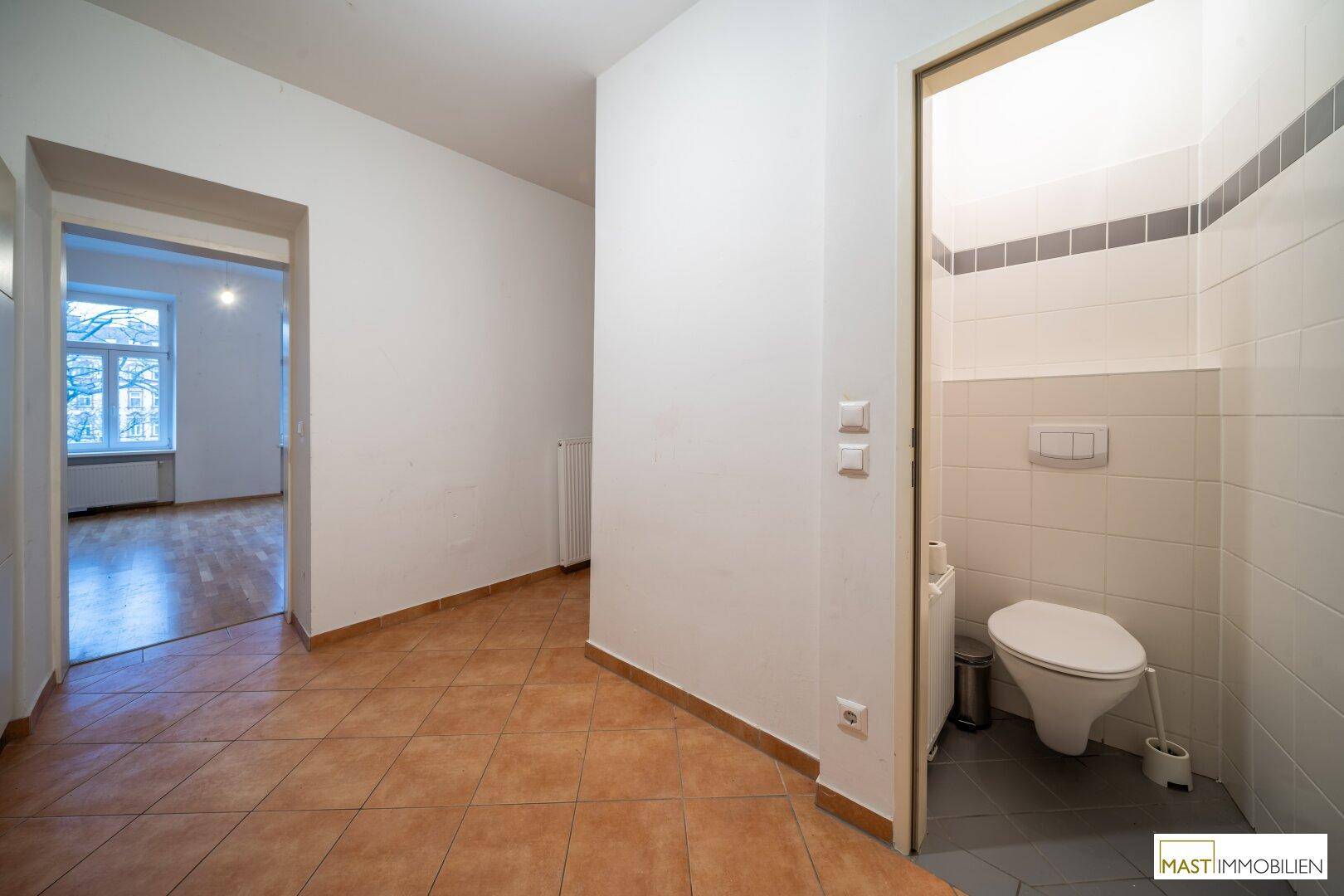 Separates WC mit Fliesenboden und Wand-WC, zugänglich vom Flur.