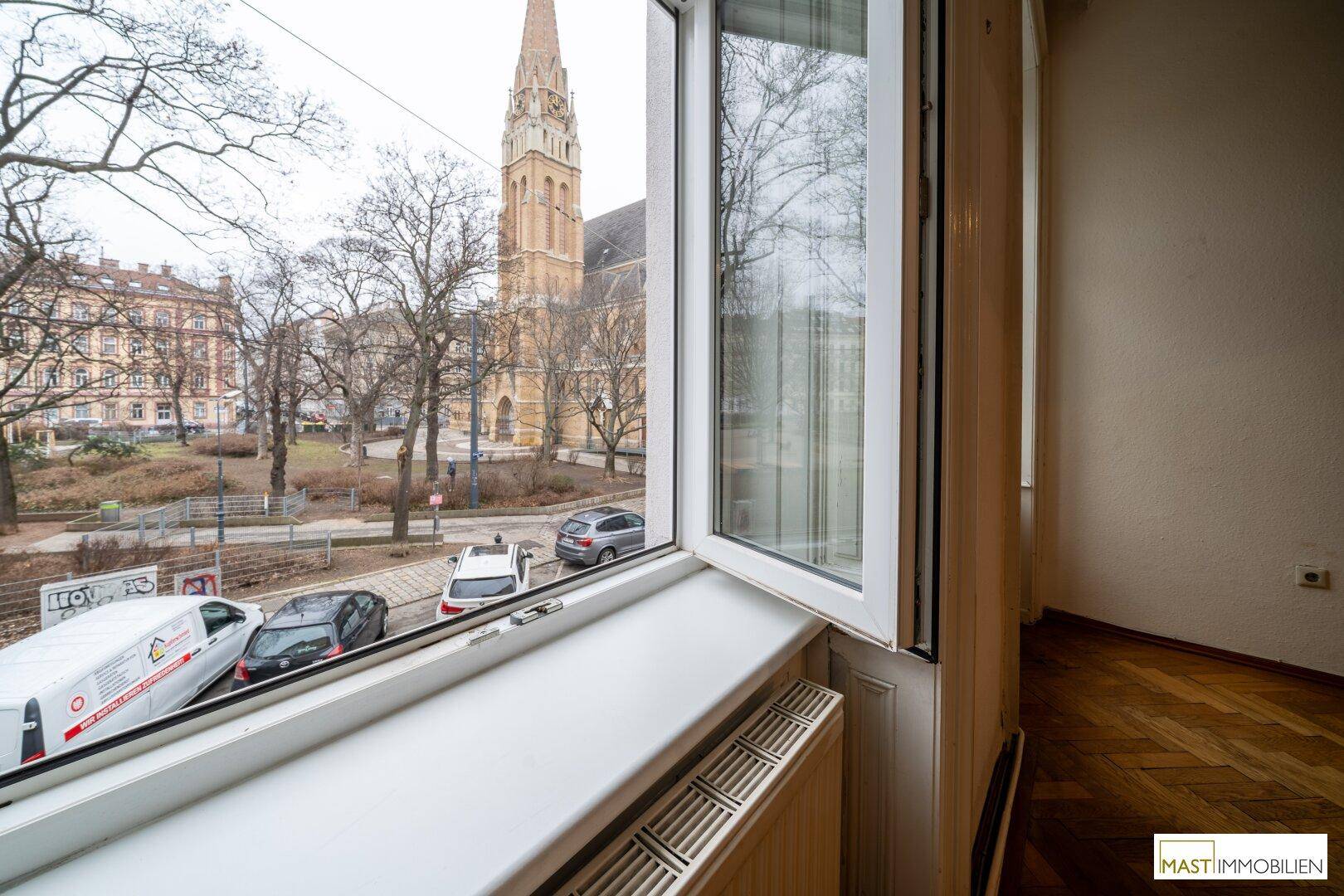 Blick aus dem Fenster auf eine Kirche und die umliegende Stadtlandschaft mit Bäumen.