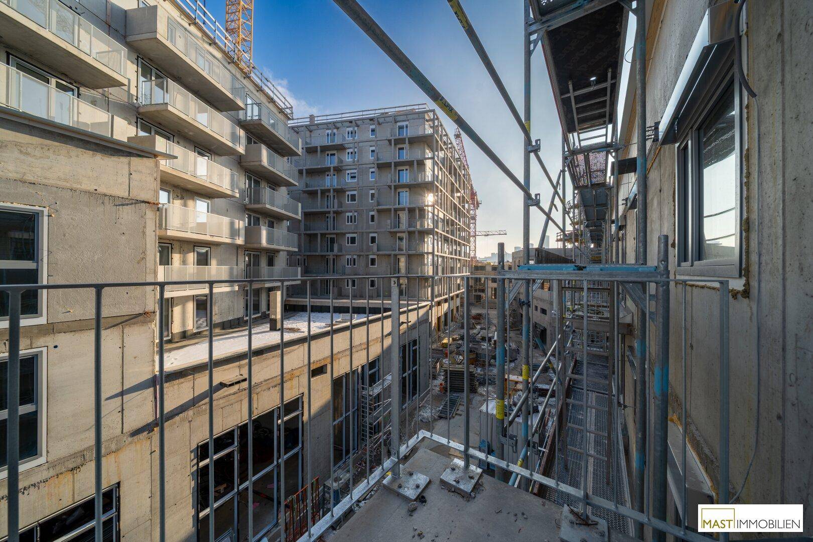 Neubaugebäude in der Bauphase mit Gerüsten und Blick auf weitere Gebäude.