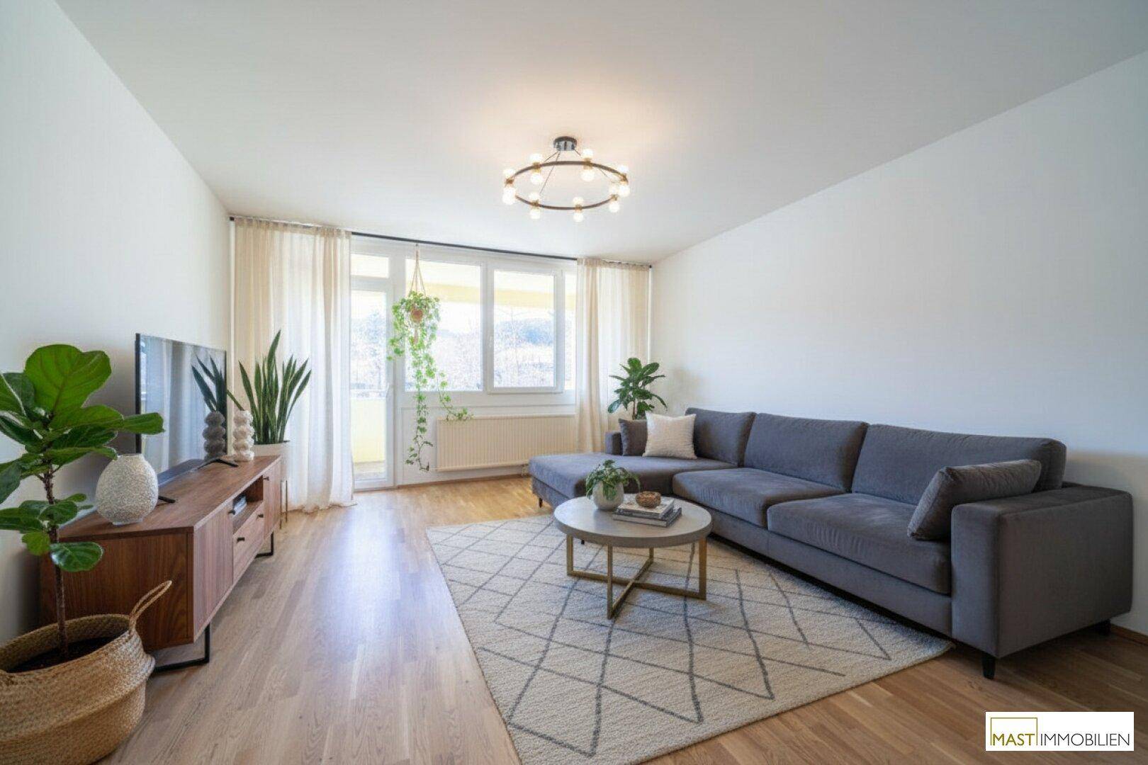 Gemütliches Wohnzimmer mit modernem Sofa, Holzboden und viel Tageslicht.