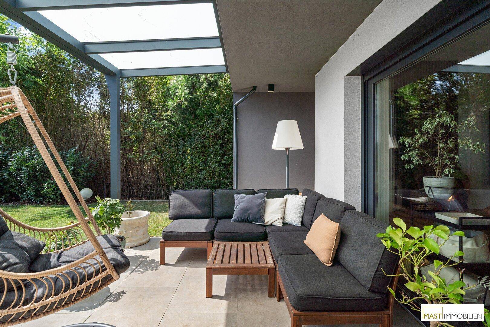 Überdachte Terrasse mit bequemen Loungemöbeln und Blick in den Garten.