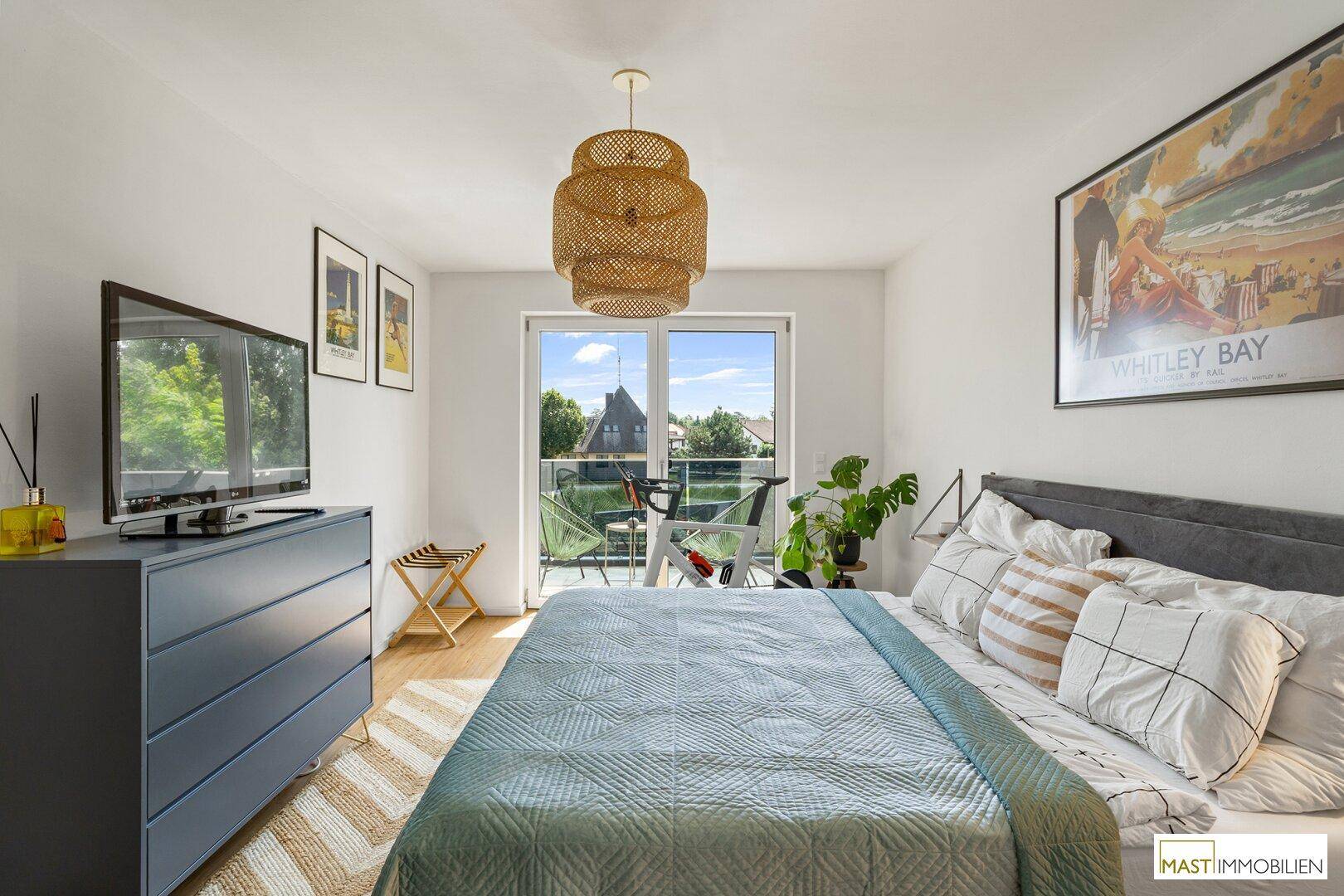 Schlafzimmer mit Doppelbett, Fernseher und Zugang zum Balkon.
