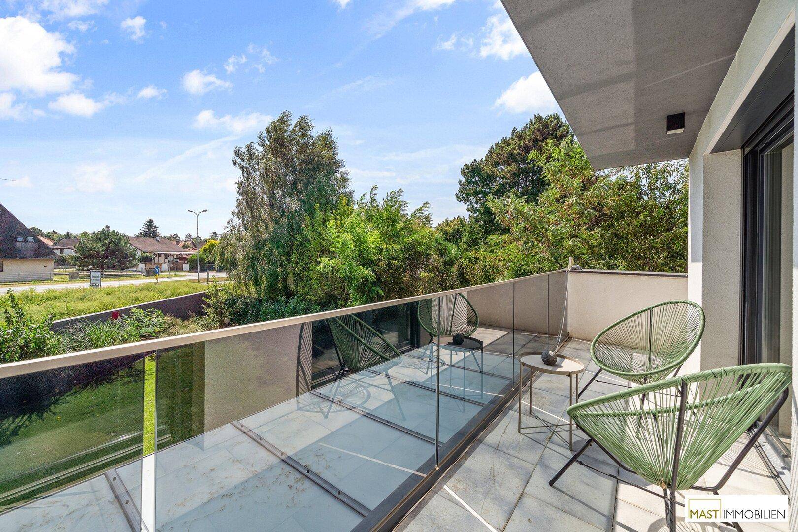 Moderner Balkon mit Glasgeländer, Sitzgelegenheiten und weitem Blick.