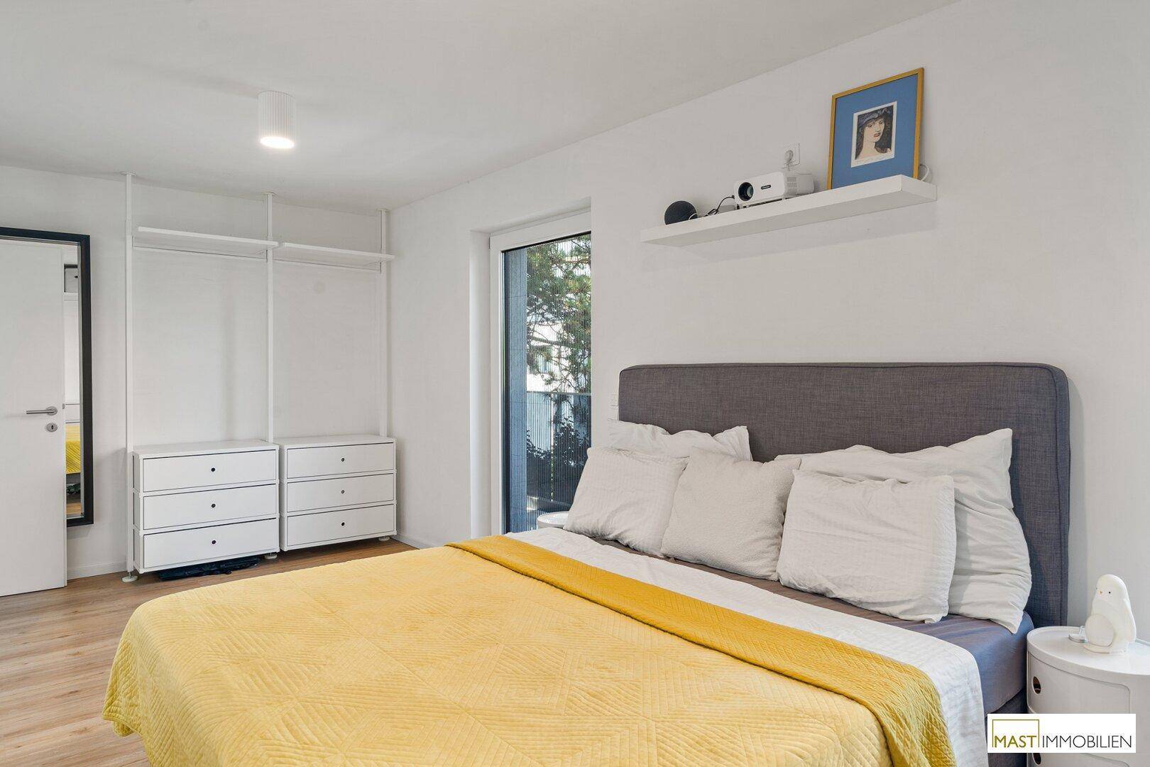 Schlafzimmer mit Doppelbett, Kleiderschrank und Fenster mit Blick ins Grüne.