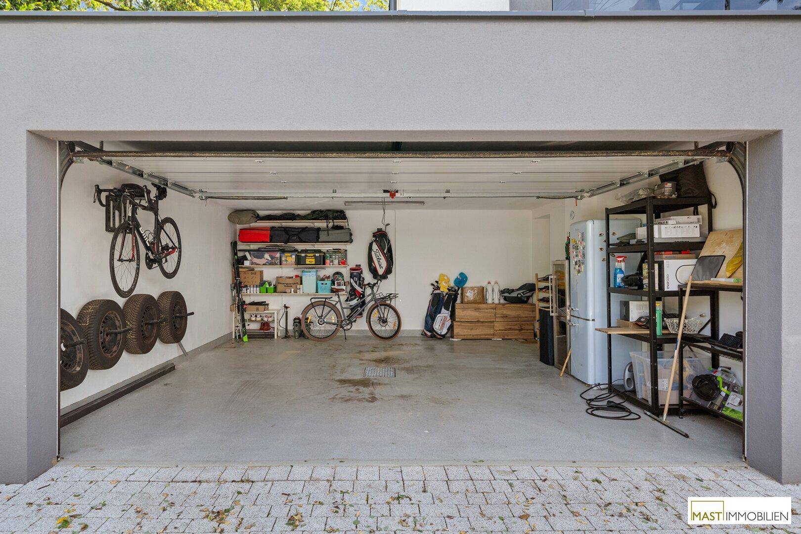 Geräumige Garage mit Stauraum, Fahrrädern und Reifenregalen.