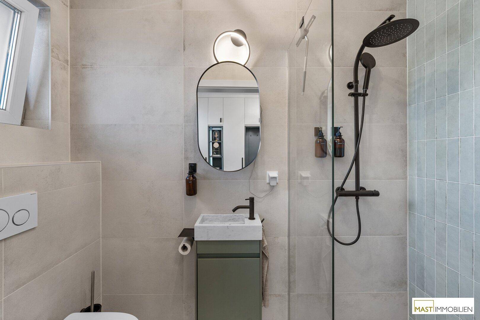 Modernes Gäste-WC mit Dusche, kleinem Waschbecken und Fenster.