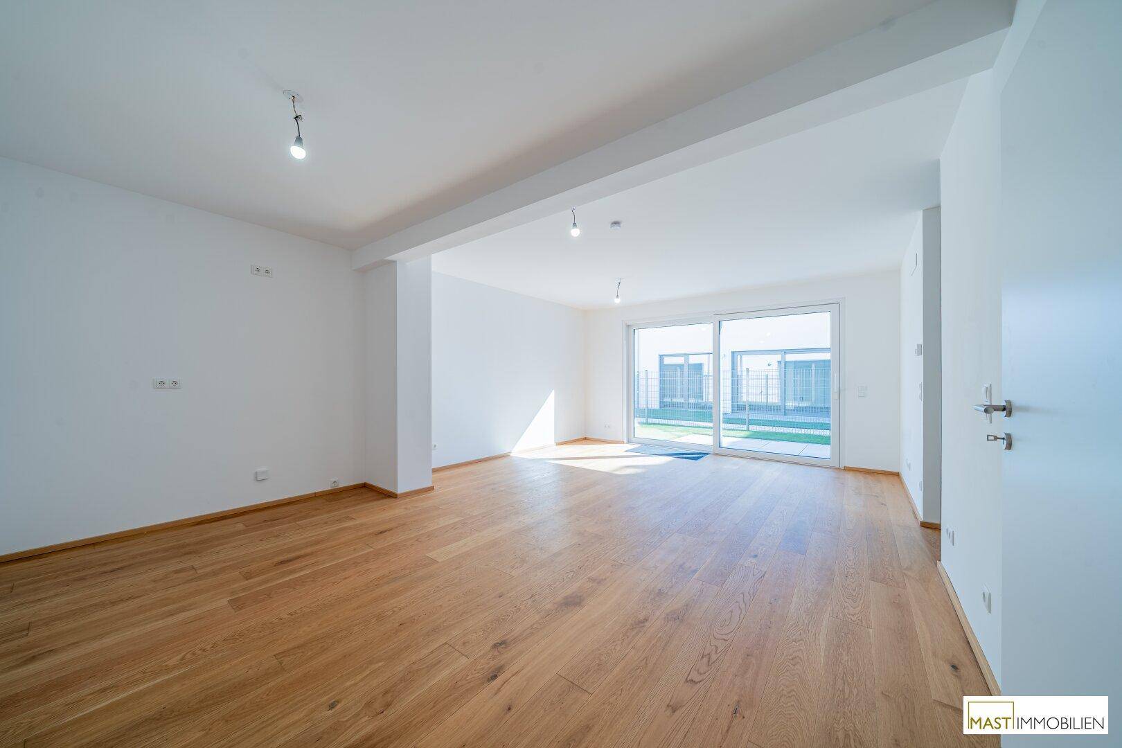 Geräumiges, helles Wohnzimmer mit Holzparkettboden und großen Schiebetüren zum Garten.