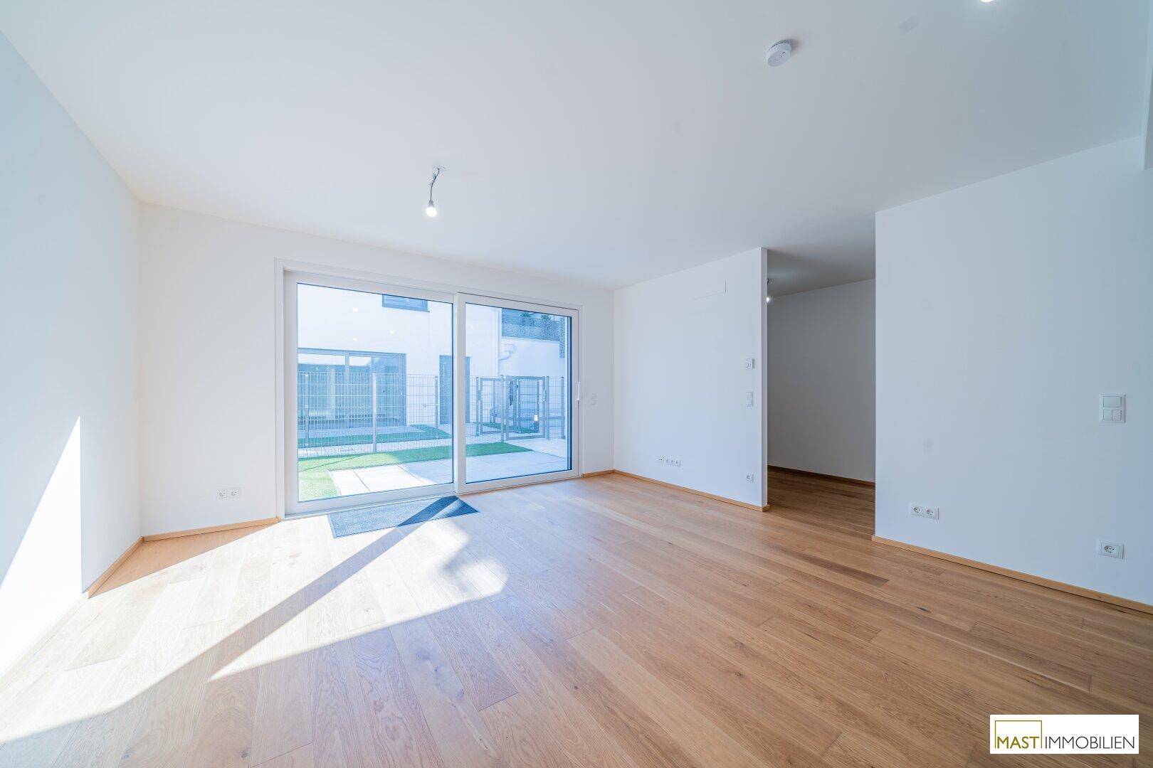 Lichtdurchfluteter Wohnbereich mit Holzboden und direktem Zugang zur Außenterrasse.