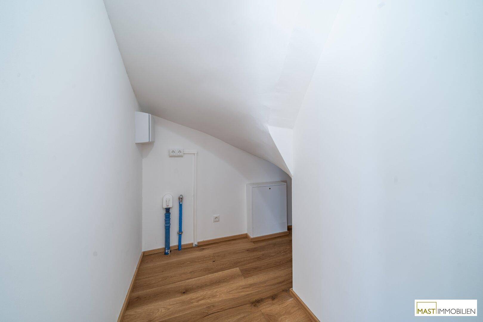 Kleiner Abstellraum mit Dachschräge und sichtbaren Installationen, ideal für Lagerzwecke.