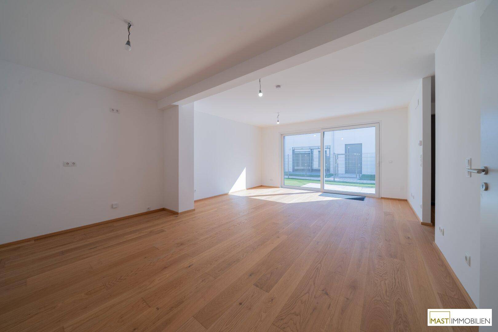 Geräumiges, lichtdurchflutetes Wohnzimmer mit Holzparkett und Zugang zur Terrasse.