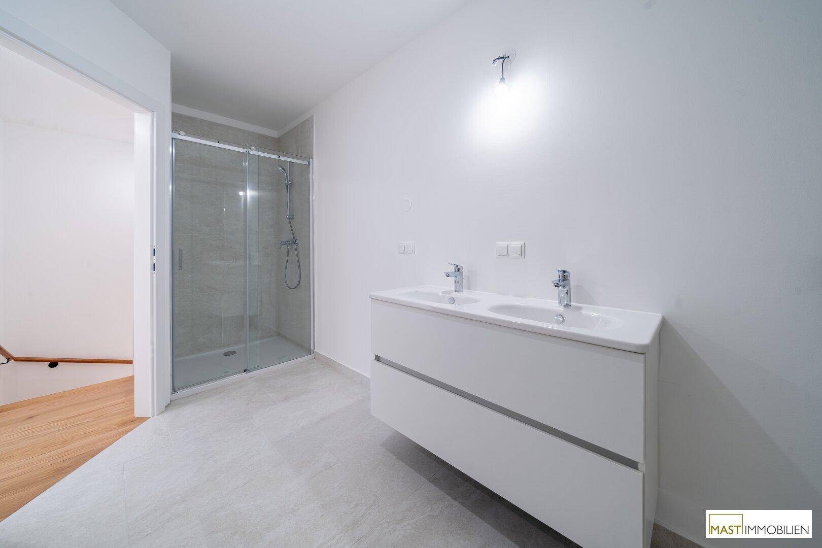 Modernes Badezimmer mit Doppelwaschbecken und einer geräumigen begehbaren Dusche.