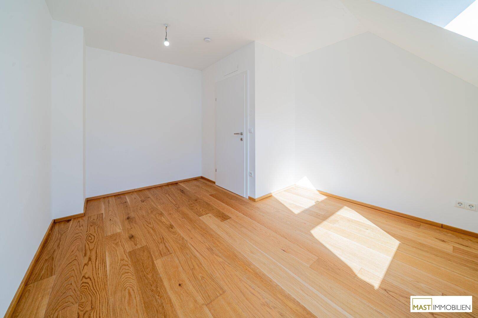 Schlafzimmer mit Holzparkettboden und weiß gestrichenen Wänden, bereit zur Einrichtung.
