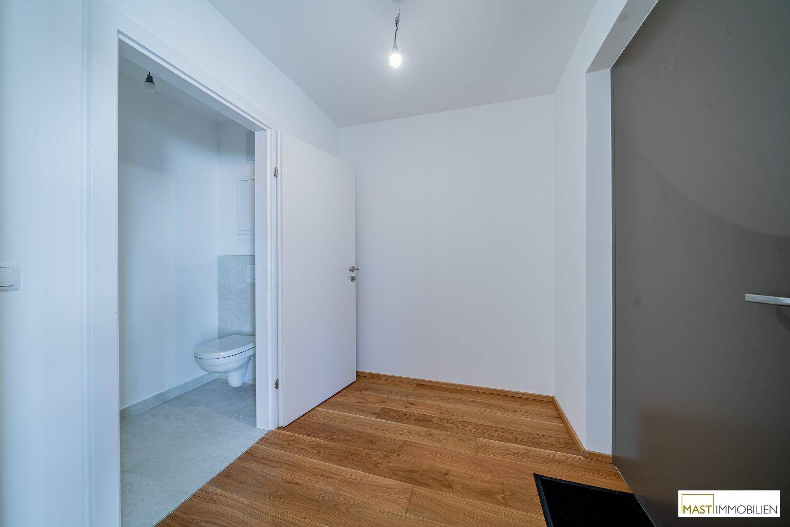 Heller Eingangsbereich mit Holzfußboden und Zugang zu einem separaten Gäste-WC.